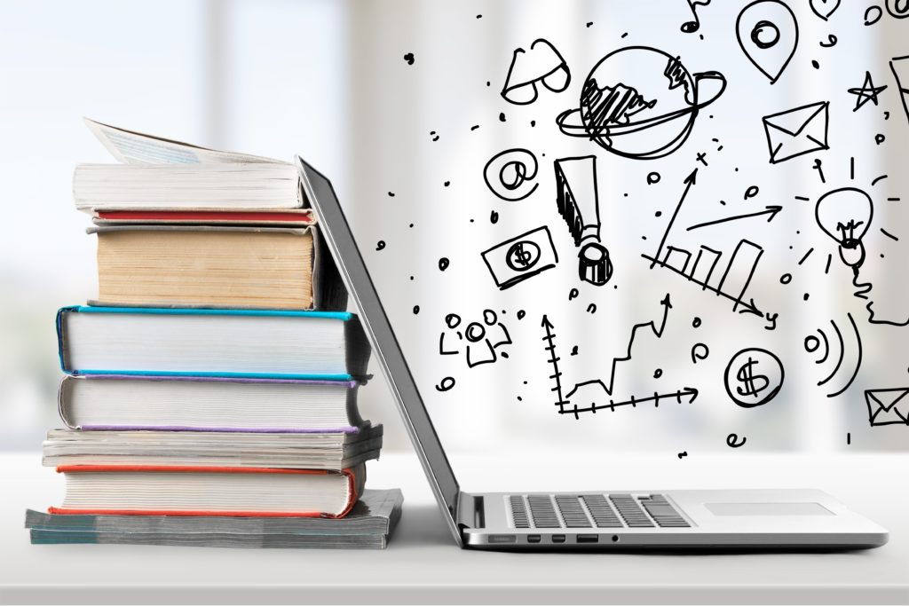 Stack of books with laptop on table