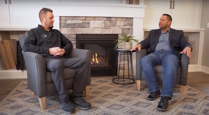 Two people sitting in chairs talking in front of a fireplace Two people sitting in chairs talking in front of a fireplace